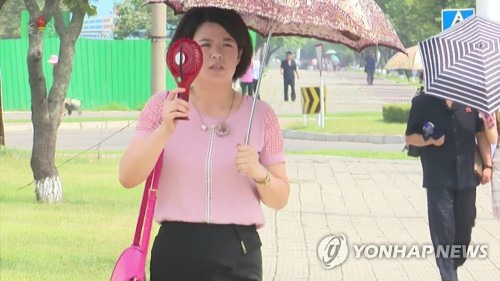 北도 가마솥더위…손 선풍기·양산 '총동원' (서울=연합뉴스) 북한에서도 기록적인 폭염이 연일 지속되면서 일부 지역에서는 낮 최고 기온이 40도를 넘어서며 기상관측 이래 가장 높은 온도를 기록했다. 사진은 조선중앙TV가 2일 공개한 영상 속에서 한 주민이 양산을 쓰고 손 선풍기를 사용하며 더위를 식히고 있다. 2018.8.2   [국내에서만 사용가능. 재배포 금지. For Use Only in the Republic of Korea. No Redistribution]  nkphoto@yna.co.kr