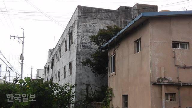 [저작권 한국일보]폐가로 방치되고 있는 외인아파트 바로 옆에 주민이 살고 있는 2층 주택이 보인다.