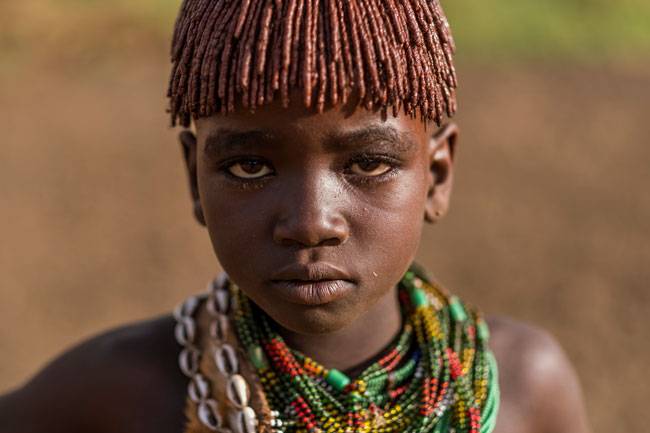 전통 방식으로 머리를 땋고 화려한 목걸이로 치장한 하메르족 소년