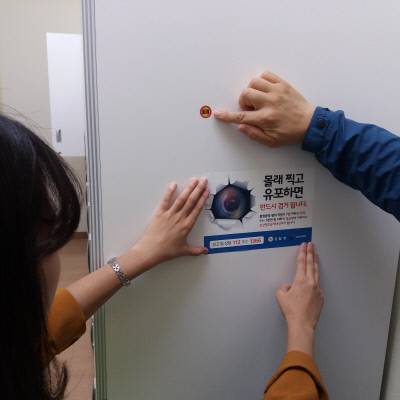 여성가족부에서 지난달 3일부터 한 달 동안 불법촬영 카메라 여부를 점검했다. 점검반이 쇼핑몰 탈의실에서 발견된 의심스러운 구멍에 스티커를 붙이고 있다.사진·여성가족부 제공