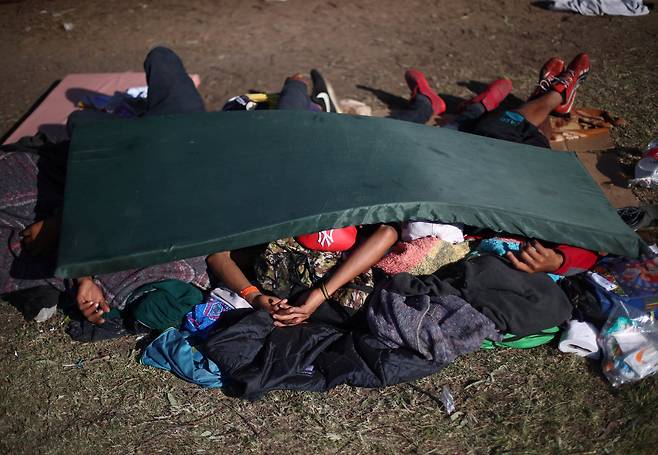 캐러밴 이민자들이 18일(현지시간) 멕시코 티후아나 시 임시 보호소 땅 바닥에서 잠을 자고 있다. [로이터=연합뉴스]