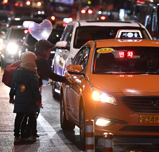 한 여성과 어린이가 성탄절 하루 전인 24일 오후 서울 종로구 종각역 인근 거리에서 차도까지 나와 택시를 잡고 있다. 권현구 기자