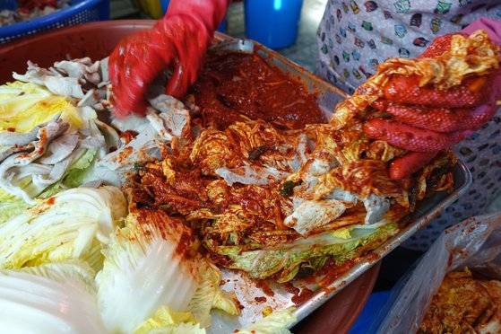 절인 배추에 양념을 바르고 갈피를 벌려 양념하지 않은 돼지고기를 두세 점씩 끼워 넣는다.