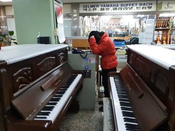 중고 피아노를 판매하는 오영미(61)씨가 혼자 가게를 지키며 전화 상담을 하고 있다. [임성빈 기자]