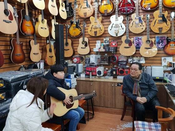 손창기(66)씨와 새 기타를 산 어린 손님이 이야기를 나누고 있다. [임성빈 기자]