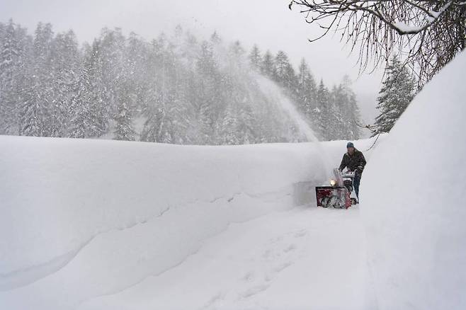 14일(현지시간) 스위스 다보스 라렛에서 한 남성이 눈을 치워 길을 만들고 있다.   폭설로 스위스 알프스산맥 대부분 지역에 눈사태 최고 단계 경보가 발령됐다./사진=뉴시스