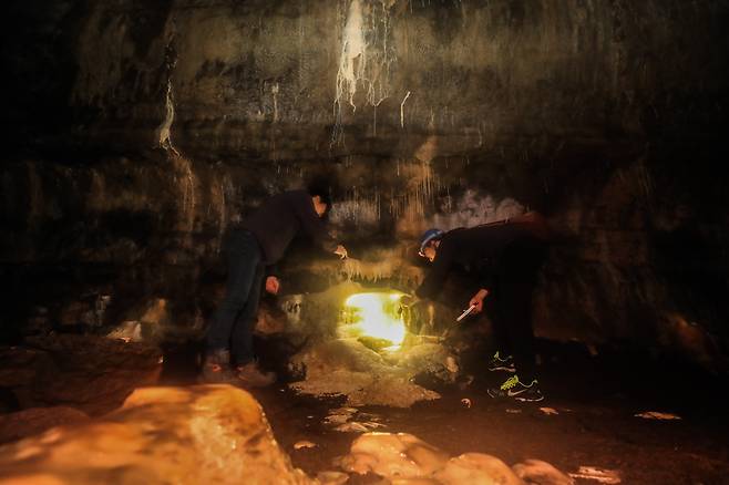 제주세계유산본부 기진석 학예연구사(왼쪽)가 용천동굴의 석회생성물을 손전등으로 비추며 설명하고 있다. 이준헌 기자 ifwedont@kyunghyang.com