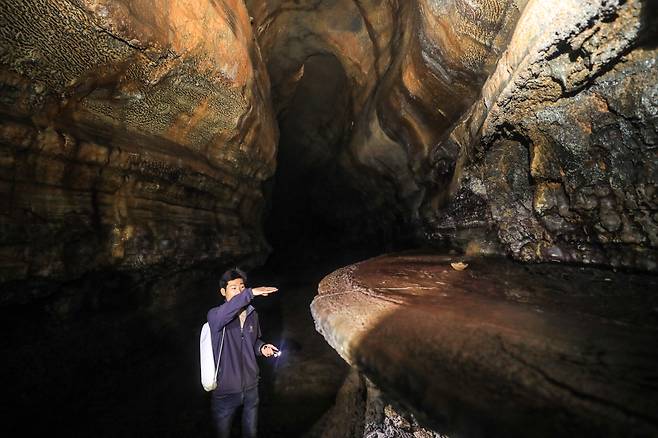제주세계유산본부 기진석 학예연구사가 동굴 벽면에 붙은 테이블 모양의 ‘용암선반’을 가리키며 설명하고 있다. 용암선반은 과거 용암이 흐른 높이를 보여주는 흔적이다. 이준헌 기자 ifwedont@kyunghyang.com
