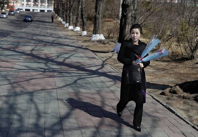 국제부녀절로 휴일인 8일 한 평양여성이 꽃을 들고 거리를 걷고 있다. [AP=연합뉴스]
