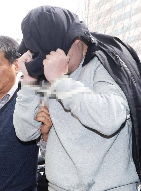 이희진씨의 부모를 살해한 용의자 김모씨가 18일 오전 조사를 받기 위해 경기 안양동안경찰서에 얼굴을 가리고 들어가고 있다. /인천일보