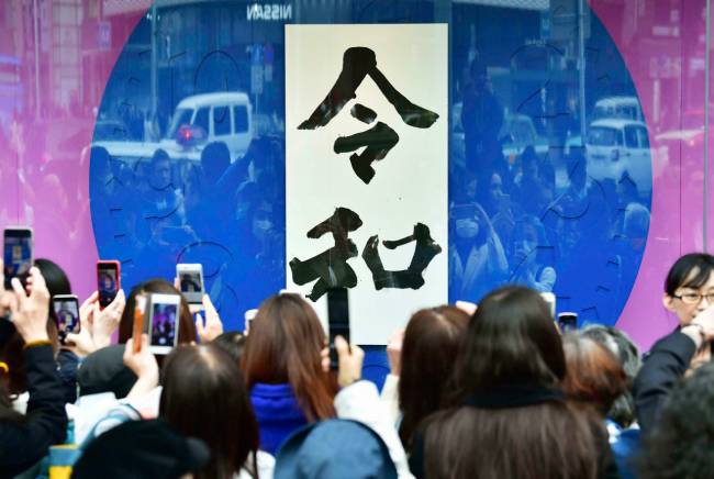 4월 1일 공개된 일본의 새 연호 ‘레이와’의 대형 서예글씨를 내건 도쿄 한 쇼윈도 앞에 사람들이 모여 사진을 찍고 있다. [AP=뉴시스]
