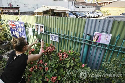 2014년 10월 12일 인도네시아 발리섬 쿠타 지역에 있는 2002년 발리 폭탄 테러 현장 주변 울타리에 한 관광객이 희생자를 추모하며 사진 등을 붙이고 있다. [EPA=연합뉴스 자료 사진]