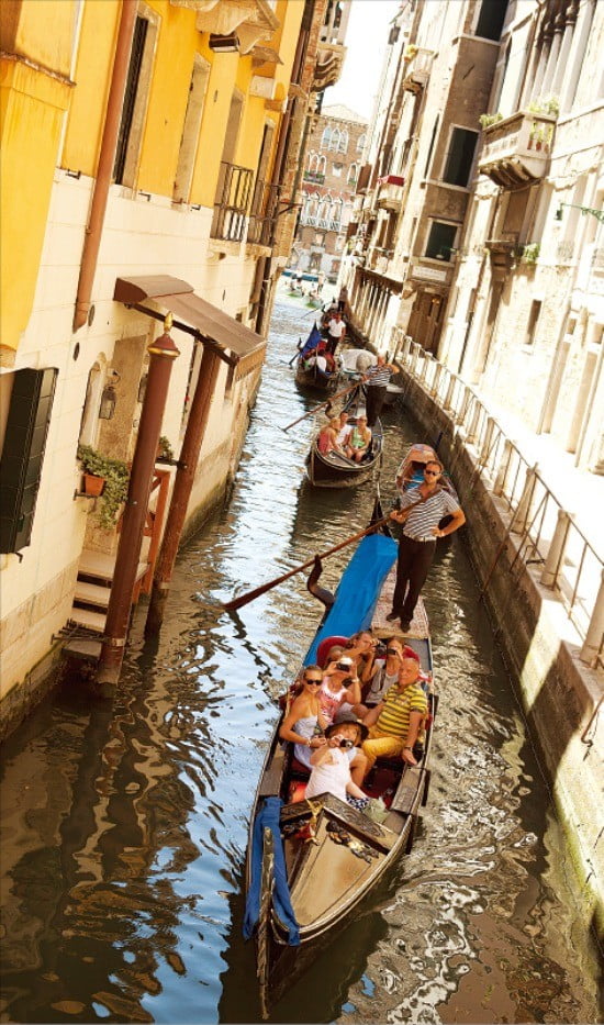 곤돌라를 타고 건물 사이 좁은 수로를 지나는 관광객들