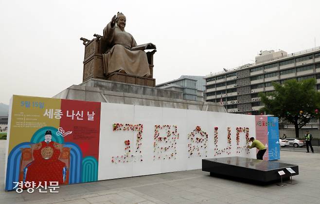 13일 오후 한 시민이 세종대왕 동상 아래 글자판에 꽃을 꽂고 있다.