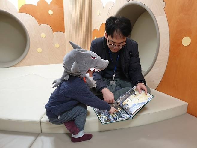 정부세종청사 5동에 있는 직장어린이집인 이든샘어린이집의 아침 풍경. 출근하기 전 아빠가 아이와 등원해 부모 대기 공간에서 책을 읽고 있다. 이든샘어린이집 제공