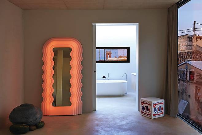 침실에는 에토레 소트사스가 디자인한 ‘울트라프라골라’ 거울이 시선을 잡아끈다. 뒤쪽에 보이는 욕조는 Inbani.