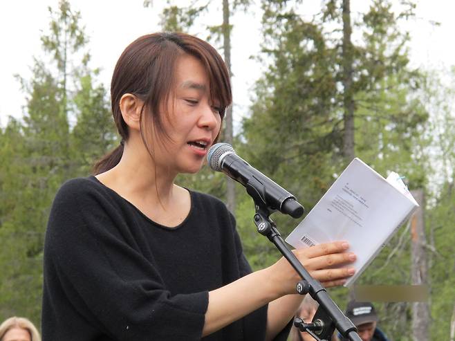 노르웨이 공공예술단체 '미래도서관'(Future Library)으로부터 올해의 작가로 선정된 소설가 한강이 25일(현지시간) 오슬로 외곽 '미래도서관 숲'에서 약 한 세기 뒤에 출간할 미공개 소설 원고의 일부를 낭독하고 있다. [연합뉴스]