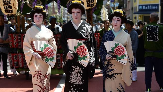 Women in kimono pose for a photograph in the street of Asakusa during Sanja festival on May 19, 2019