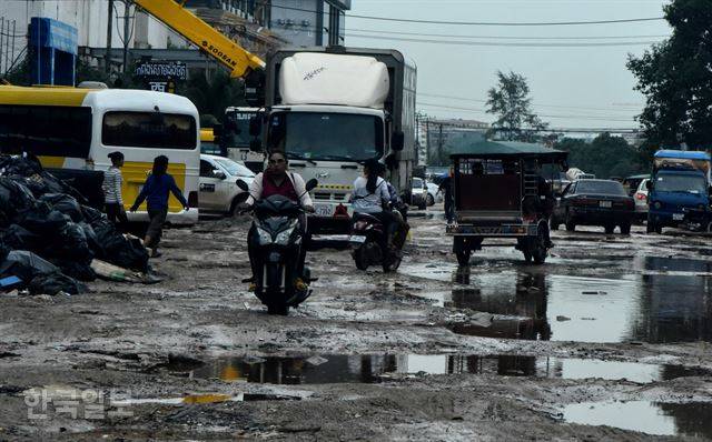 시아누크빌 시내 거리 풍경. 중국 자본에 의한 호텔, 카지노, 아파트 공사가 한창이다. 공사장에서 나온 쓰레기, 공사장 차량들이 지나면서 망가져 움푹 패인 도로의 물을 피해 자동차와 오토바이들이 위태롭게 달리고 있다.