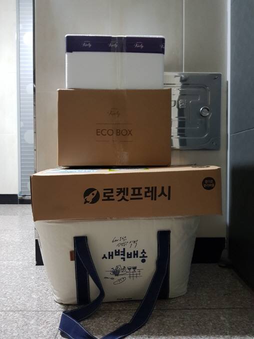 현관문 앞에 쓱닷컴(아래부터), 쿠팡, 마켓컬리의 새벽배송 주문 상품이 도착해 있다. 마켓컬리는 타사와는 달리 박스가 2개 왔다. (사진=강신우 기자)
