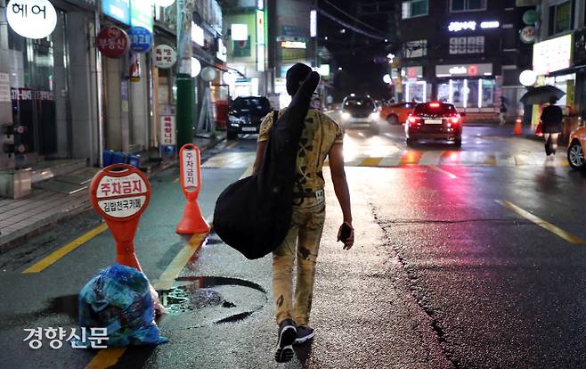 아미두가 악기를 둘러메고 지하철을 나와 집으로 향하고 있다.