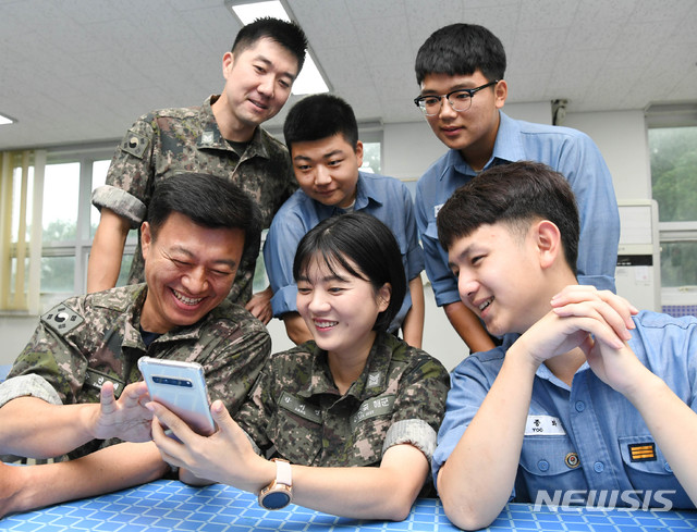 【서울=뉴시스】 덕적도 해군기지에 근무하는  여군 전탐부사관 강서연 중사(가운데)가 동료들과 아이 사진을 보며 환하게 웃고 있다. (해군 제공)