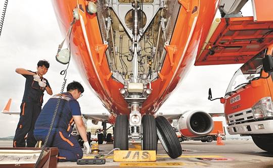 비행기 앞 타이어 마모 상태를 확인한 정비사가 새로운 타이어를 교체하기 위해 준비하고 있다.