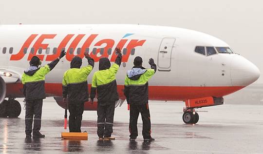 JAS 직원들이 비행기의 이륙 준비를 마치고 승객들에게 손을 흔들고 있다.