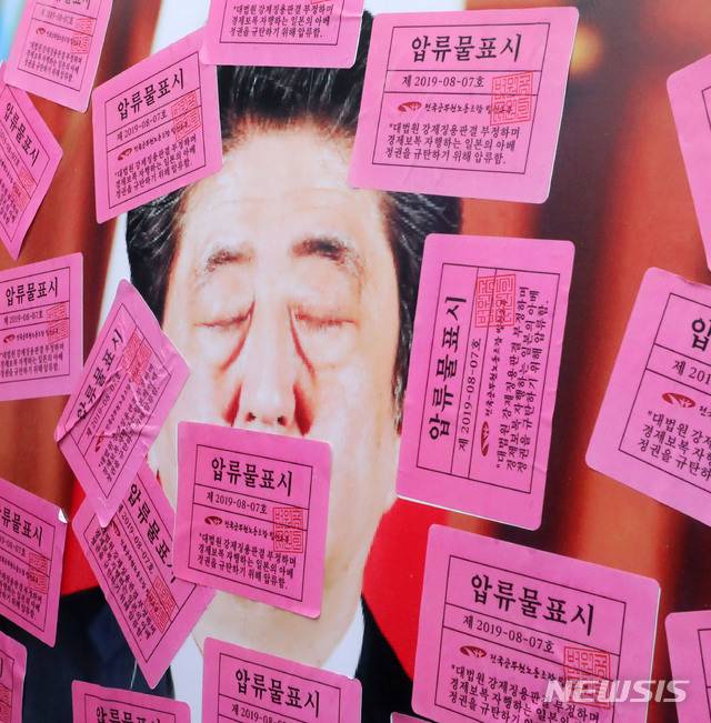 【서울=뉴시스】박주성 기자 = 법원 노조가 7일 오전 서울 종로구 주한 일본대사관 앞에서 대법원 강제징용 판결 부정하는 아베 정권 규탄 법원공무원 기자회견 중 아베 사진과 일본 전범기업 사진에 압류물표시 스티커를 붙이고 있다. 2019.08.07. park7691@newsis.com