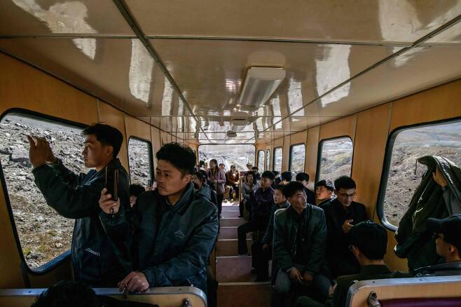 북한 주민들이 지난 11일 백두산 정상으로 가는 케이블 기차를 타고 주변 풍경을 카메라에 담고 있다. [AFP=연합뉴스]