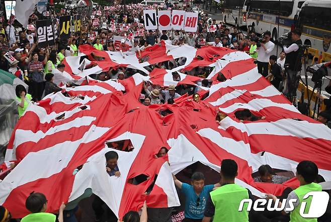 지난 7월20일 서울 종로구 옛 일본대사관 앞에서 열린 일본의 경제보복과 아베 신조 일본 총리를 규탄하는 촛불집회가 끝난 뒤 참석자들이 대형 욱일기를 찢는 퍼포먼스를 하고 있다. © AFP=뉴스1