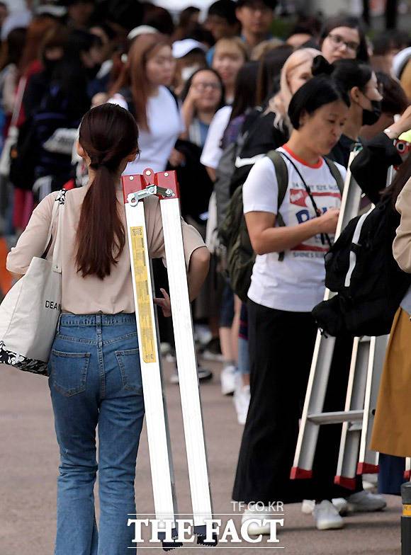 어깨에 사다리를 매고 가는 한 여성 의 모습. 높은 곳에 올라가서 찍어야 하기에 이들에게 사다리는 필수다.