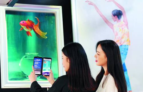 시민들이 18일 공덕역 팝업 갤러리에서 임경식 작가의 ‘꿈을 꾸다’ 작품을 보고 있다. 스마트폰으로 작품을 비추면 그림 속 금붕어가 마치 생명을 얻은 듯 움직이기 시작한다.
