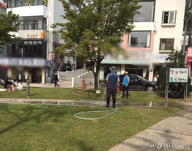 연남동 공원에서 잔디에 물을 주고 있는 조경관리사 두 분./사진=남형도 기자