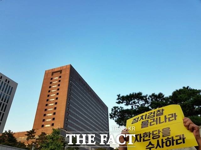 한 시민이 서울 서초동 서울중앙지검 앞에서 열린 '제7차 검찰개혁 촛불문화제'를 앞두고 "정치검찰 물러나라. 자한당(자유한국당)을 수사하라"는 피켓을 들고 있다. 뒤에 보이는 건물은 서울중앙지검. /송주원 기자