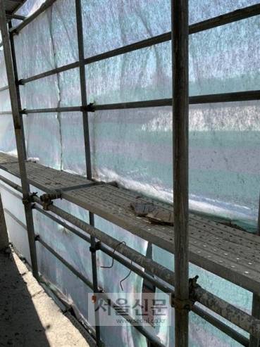 불량 - 서울의 한 빌라 공사장에 설치된 강관 비계의 모습. 노동자가 지나다니는 발판 위로 난간이 안전하게 최소 두 줄로 설치돼 있어야 하지만 듬성듬성하게 돼 있다. 발판 위도 정돈돼 있지 않고 쓰다 남은 건설자재가 뒹굴고 있다.