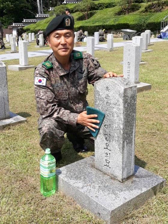 전인석 육군 35사단 전주대대 전주 완산구지역대장이 지난달 27일 전주 교동 군경묘지를 찾아 6·25 전쟁 때 전사한 고 이점수(아명 이상오) 하사의 묘비를 닦고 있다. [사진 35사단]