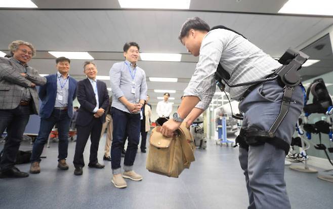 현대자동차 의왕연구소에서 열린 제1차 스마트농업 현장 포럼에서 한 참가자가 웨어러블 슈트를 장착하고 물건을 드는 작업을 시연했다. [자료:농림축산식품부]