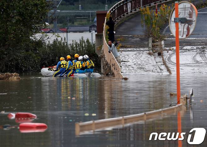 태풍 하기비스가 몰고 온 폭우로 14일 일본 나가노현 나가노시 지쿠마강에 제방이 무너져 주변 가옥과 다리가 침수, 한 남성이 침수된 지역을 수색하는 구조대원들과 이야기를 나누고 있다. © 로이터=뉴스1 © News1 이동원 기자