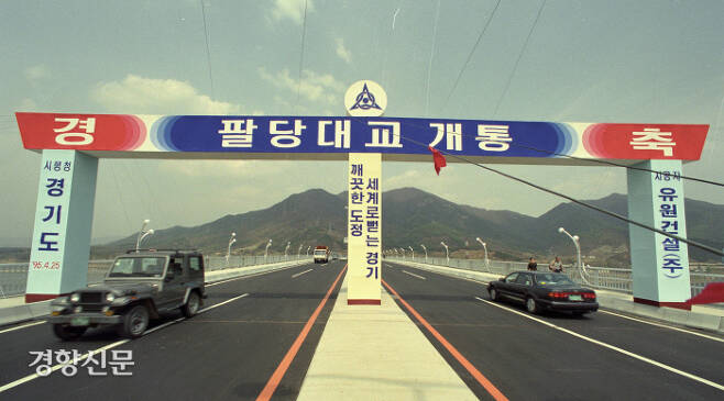 1986년 착공해 1995년 4월 완공된 팔당대교의 개통 기념 플래카드 아래로 차량들이 지나고 있다. 경향신문 자료사진