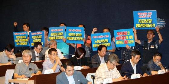 지난해 8월17일 오후 서울 중구 세종대로 대한상공회의소 의원회의실에서 열린 '국민연금 제도개선 방향에 관한 공청회'에서 공적연금강화 국민행동 소속 회원들이 '지급 보장 명문화' 등을 촉구하는 손 피켓을 들고 구호를 외치고 있다. [뉴시스]