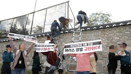 한국대학생진보연합 소속 대학생이 18일 오후 서울 중구 주한 미국대사관저에서 방위비분담금 협상 관련 기습 농성을 하기 위해 담벼락을 넘고 있다. [뉴시스]