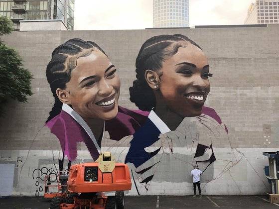 지난 10월 미국 LA에서 LG유플러스와 애플 아이폰11 프로 공동 광고를 위해 다운타운 뮤직센터의 가로 30m, 세로 15m 규모의 대형 벽면에 한복을 입은 외국인 여성을 그리고 있는 장면. [사진 LG유플러스]