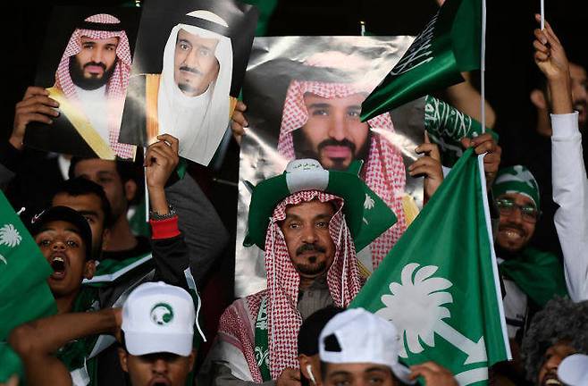 사우디아라비아 축구 팬들이 살만 빈 압둘아지즈 알사우드 국왕과 아들 무함마드 왕세자 사진을 들고 있다/사진=AFP