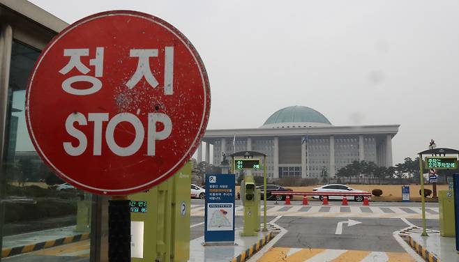 지난달 29일 자유한국당의 '필리버스터' 기습 선언으로 패스트트랙 법안과 예산안 등의 일괄 처리가 어려워졌다. 예산안 법정 처리시한을 하루 앞둔 그리고 패스트트랙 법안 중 검찰개혁 법안이 이틀 뒤 본회의에 부의되는 1일 오후 국회 출입문 교통표지판 너머로 국회 본관이 보인다. [연합]