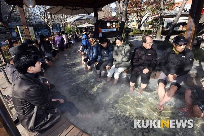 유성구 온천공원 내 족욕체험장에서 발을 담그고 온천욕을 즐기는 시민과 관광객들