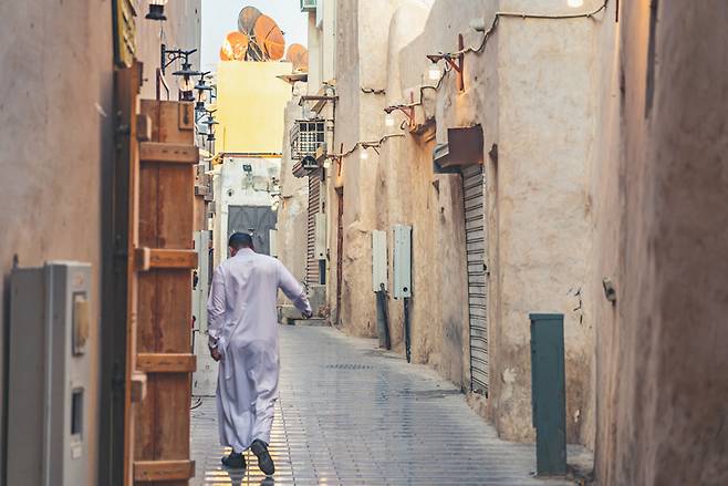 싸웁을 걸친 한 남성이 후푸프 시장 옆 골목을 걷고 있다