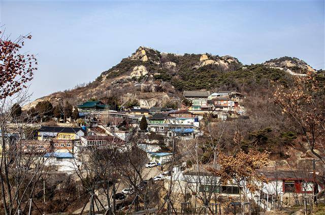 서울 서대문구 현저동 언덕에서 바라본 선바위와 국사당을 품은 인왕산 풍경. 작가 박완서가 50세에 쓴 ‘엄마의 말뚝 1·2’에 이어 62세에 출간한 ‘그 많던 싱아는 누가 다 먹었을까’, 65세에 쓴 ‘그 산이 정말 거기 있었을까’ 등 자전적 연작소설 3부작이 잉태된 그의 문학의 고향이다.