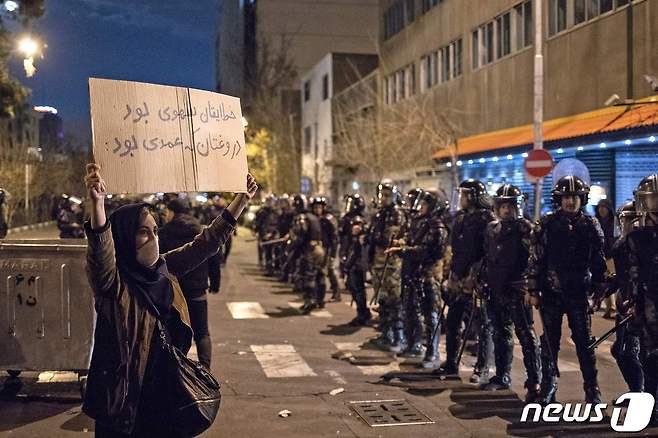 11일(현지시간) 이란 수도 테헤란 아미르카비르 대학에서 열린 반정부 시위에서 한 여성이 "당신의 실수는 의도한 것이 아니다. 하지만 당신의 거짓말은 고의적이다"는 플래카드를 들고 있다. © AFP=뉴스1