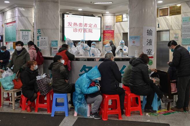 지난 24일 중국 우한의 한 병원에서 사람들이 진료를 기다리고 있다. 뒤로는 보호장구를 착용한 메디컬 스태프의 모습이 보인다. [AFP=연합뉴스]